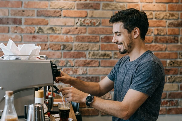 Man smiling and chatting kindly with a cafe barista, illustrating the attractiveness of warmth toward service staff