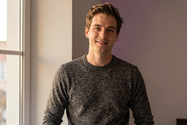 Founder in charcoal sweater at a sunlit window, representing the BeyondSize founding team